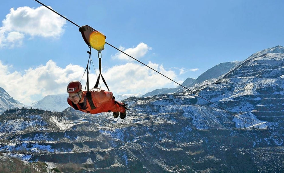 zipworld man going very fast on a zipline over a lake